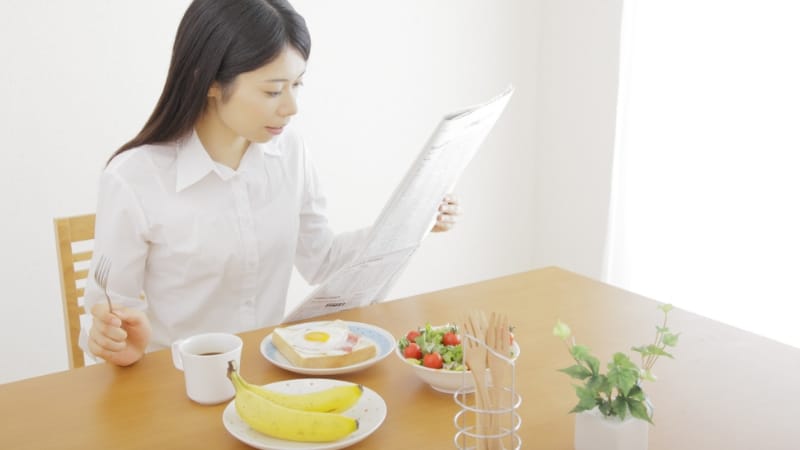 女性が朝刊を読んでいる様子
